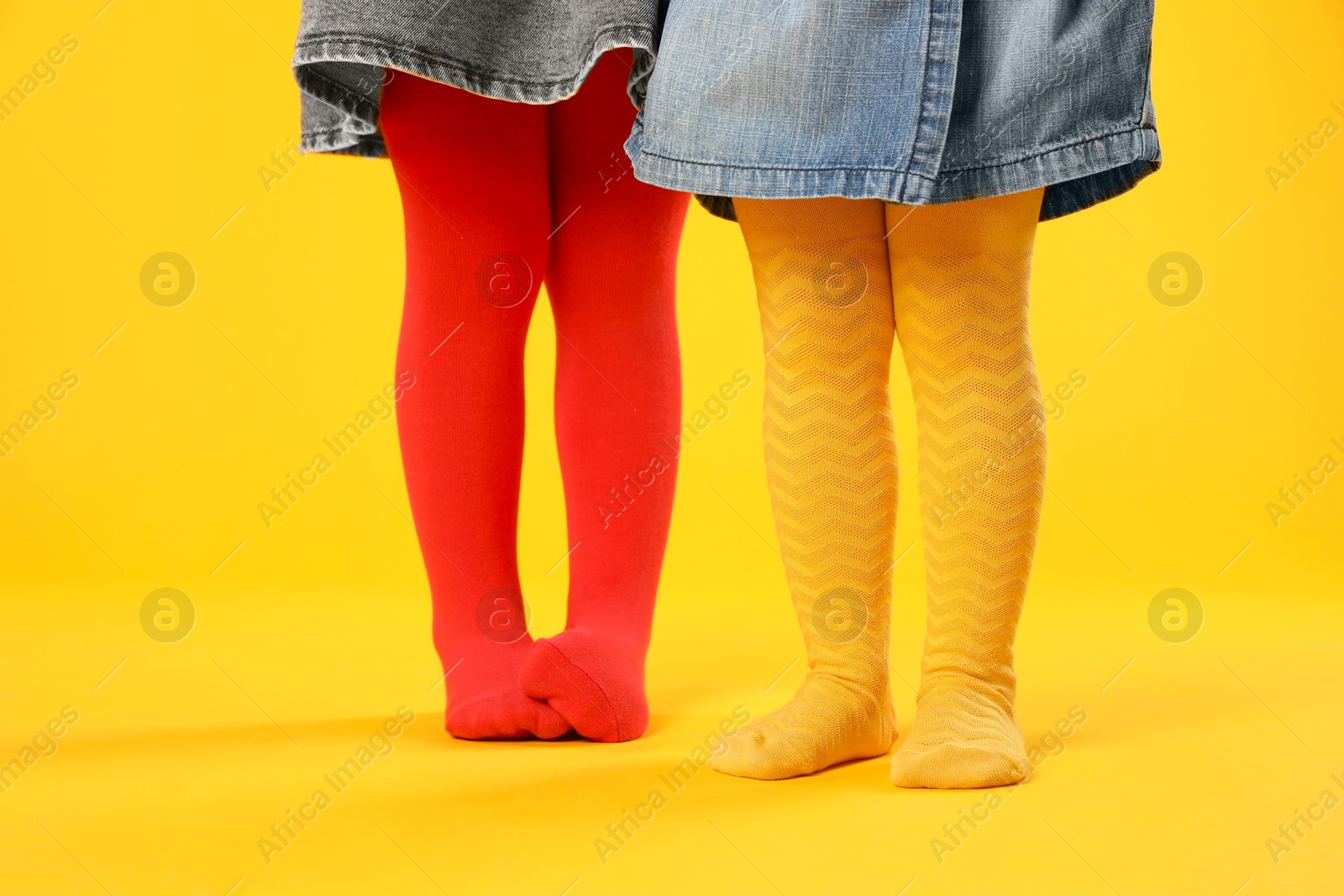 Photo of Kids wearing colorful tights on orange background, closeup