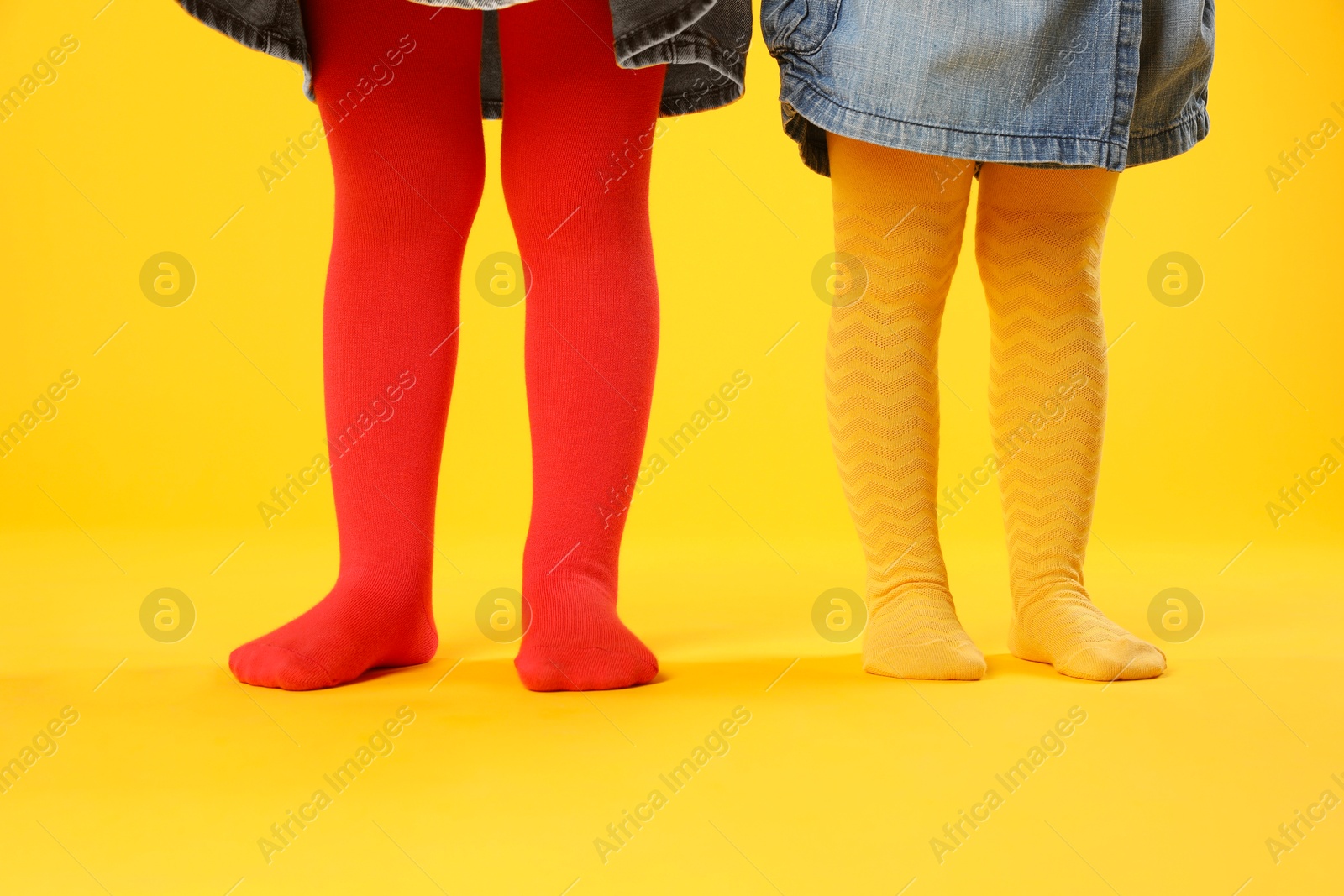 Photo of Kids wearing colorful tights on orange background, closeup