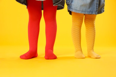 Photo of Kids wearing colorful tights on orange background, closeup