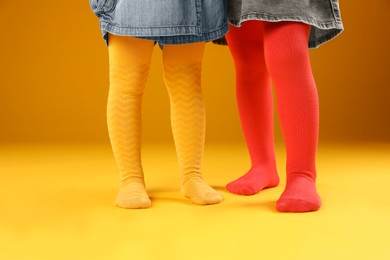 Photo of Kids wearing colorful tights on orange background, closeup