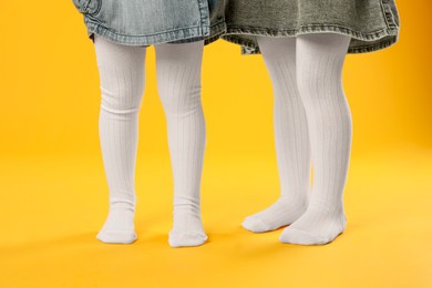 Photo of Kids wearing tights on orange background, closeup