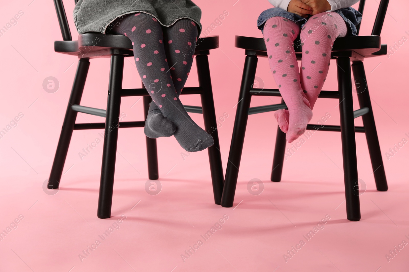 Photo of Kids wearing tights on chairs against pink background, closeup