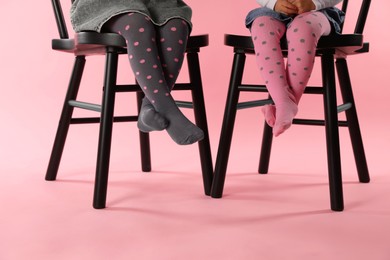 Photo of Kids wearing tights on chairs against pink background, closeup