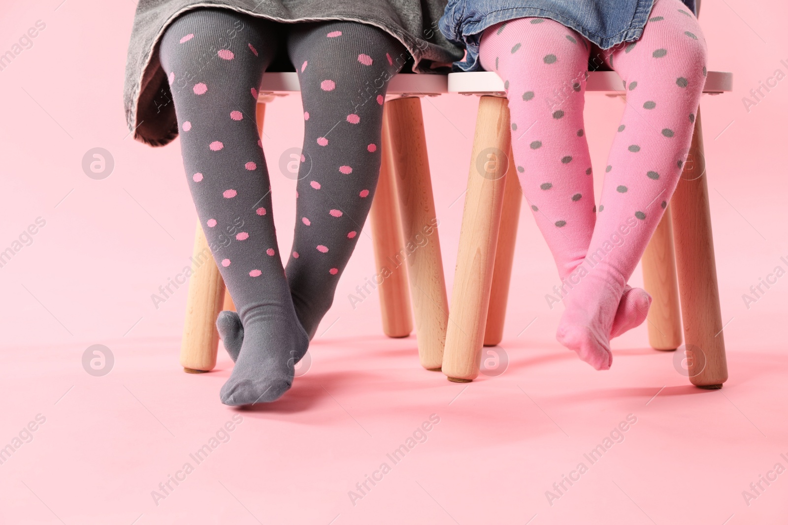 Photo of Kids wearing tights on stools against pink background, closeup