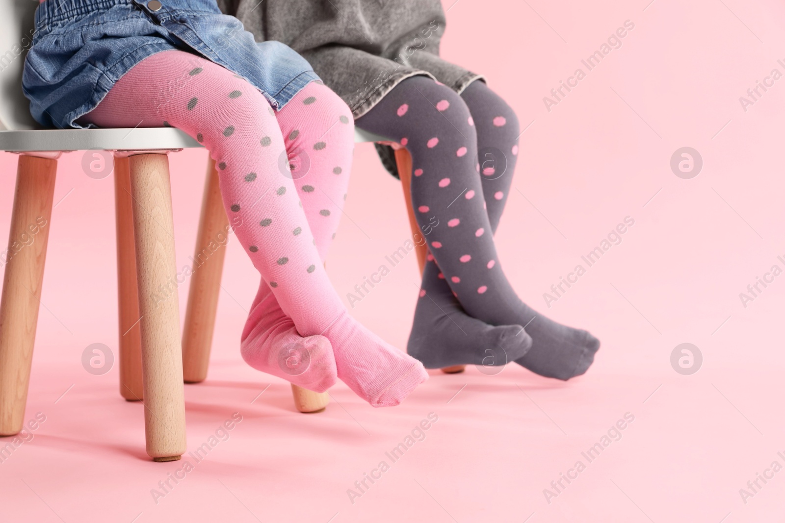 Photo of Kids wearing tights on stool against pink background, closeup. Space for text