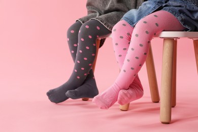 Photo of Kids wearing tights on stool against pink background, closeup. Space for text