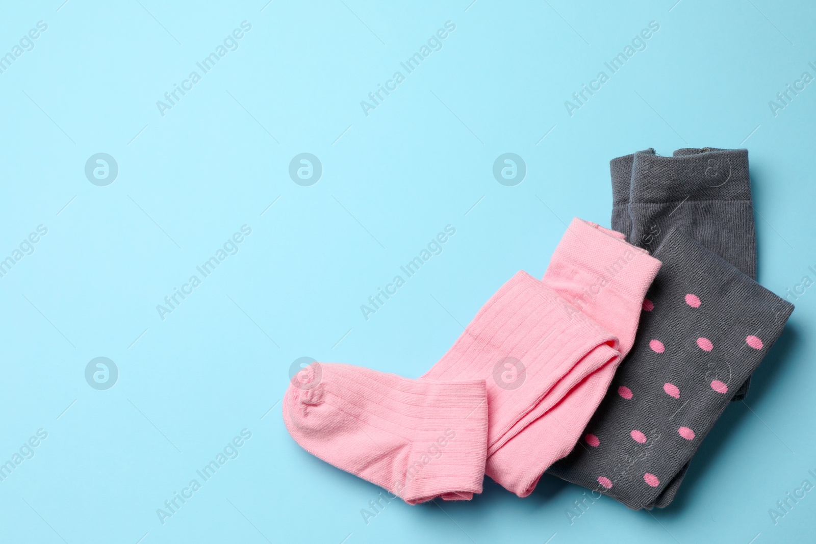 Photo of Different child's tights on light blue background, top view. Space for text