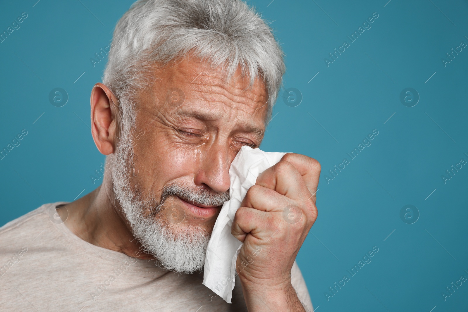 Photo of Sad senior man crying on light blue background