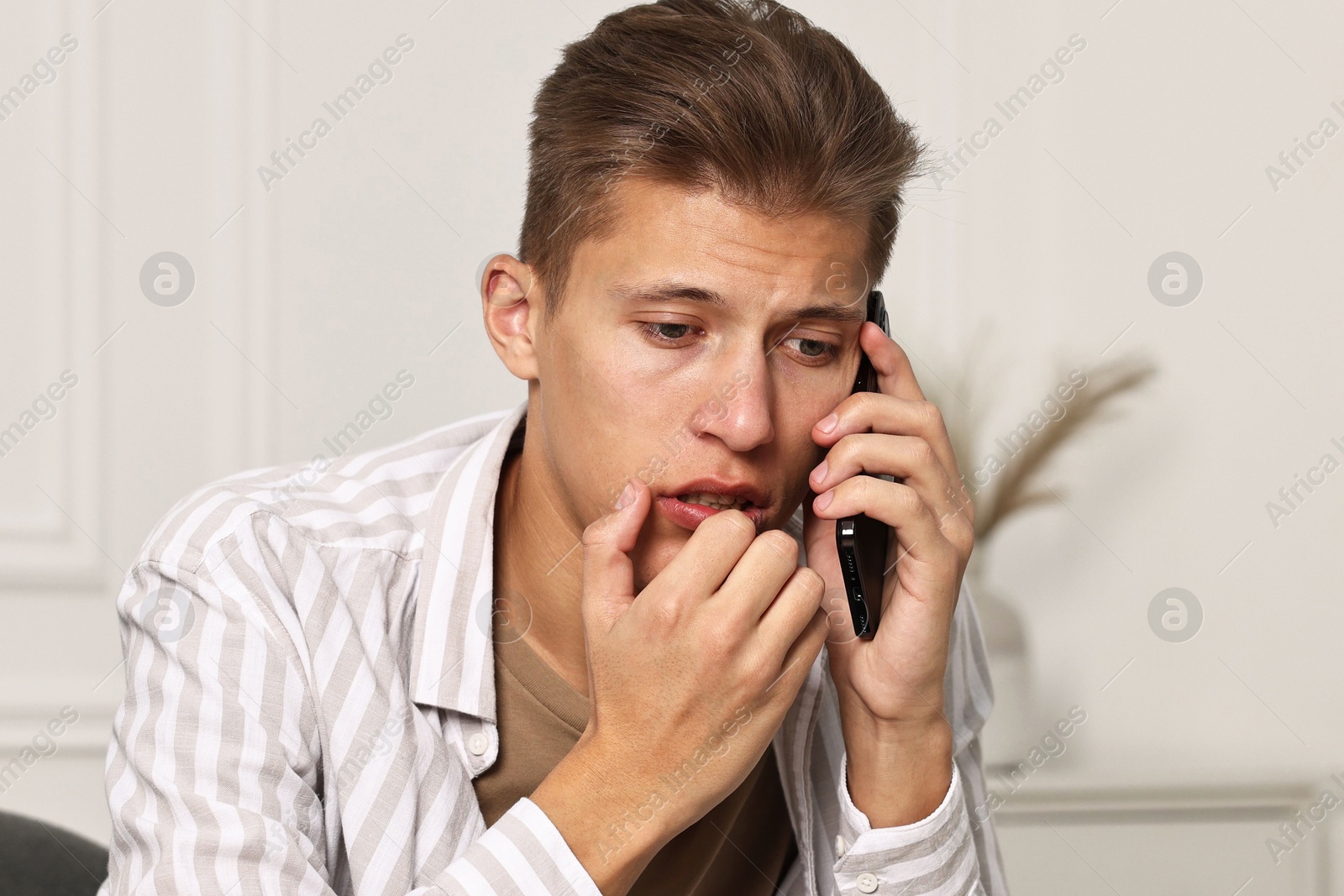 Photo of Worried man calling hotline for mental health help at home