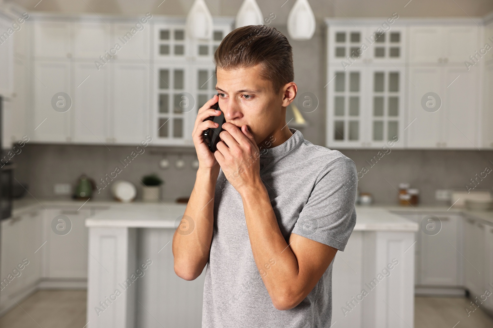 Photo of Worried man calling hotline for mental health help in kitchen