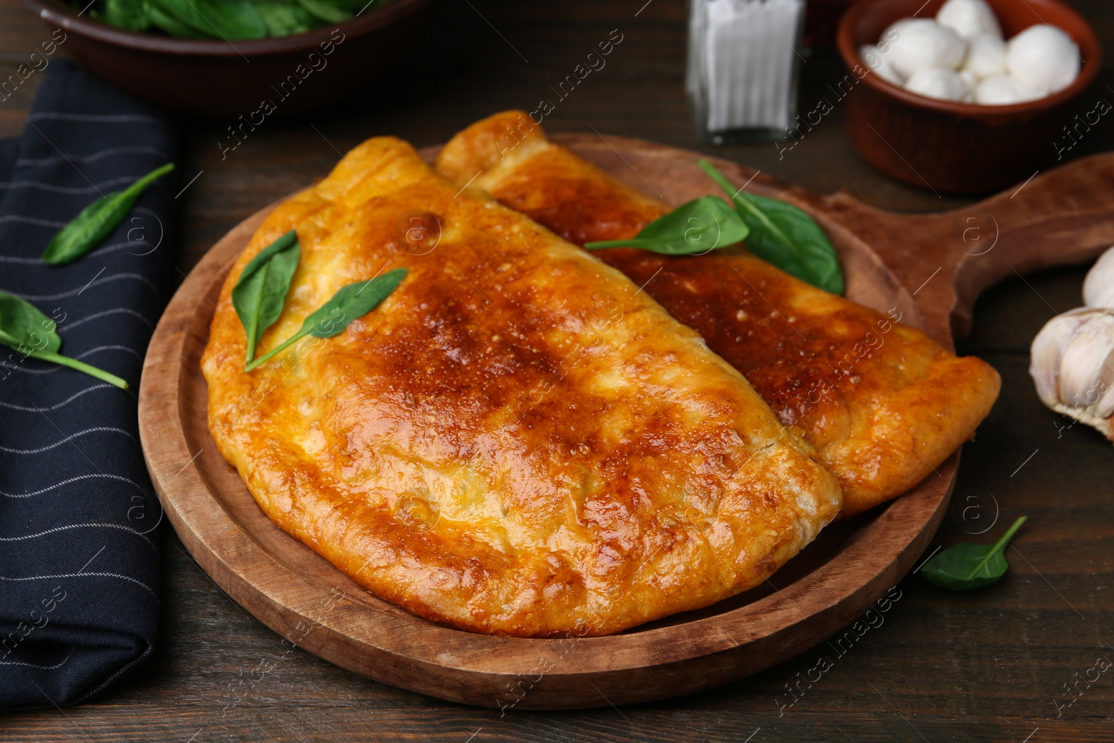 Photo of Tasty calzones with basil and mozzarella cheese on wooden table, closeup