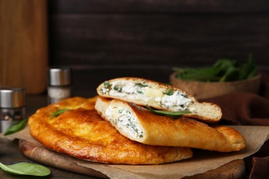 Photo of Tasty calzones with cheese and basil on table, closeup