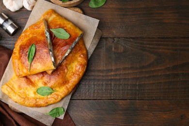 Photo of Tasty calzones with cheese and basil on wooden table, top view. Space for text