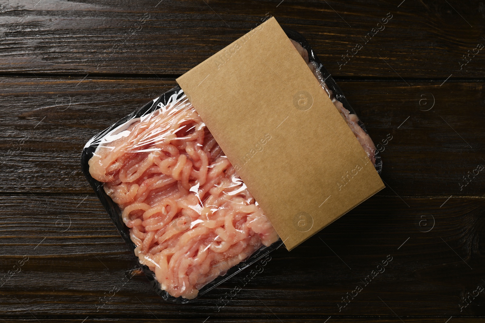 Photo of Plastic pack with fresh minced meat on wooden table, top view