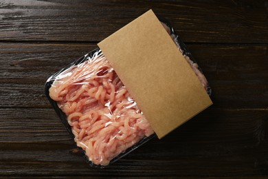 Photo of Plastic pack with fresh minced meat on wooden table, top view