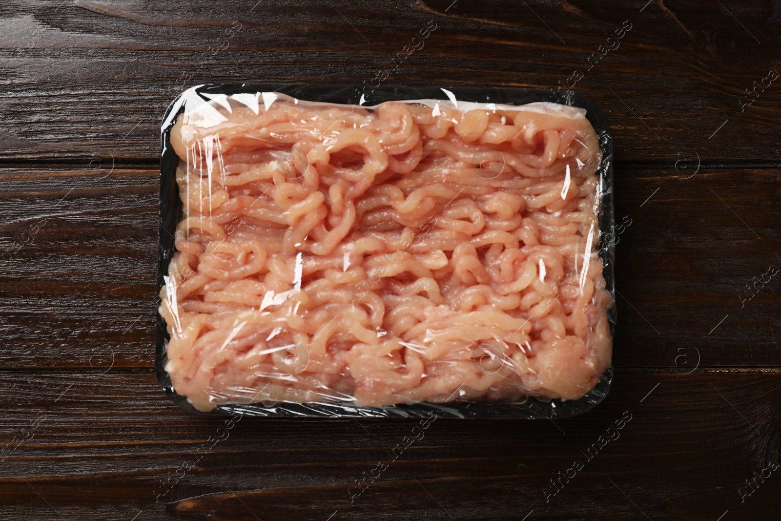 Photo of Plastic pack with fresh minced meat on wooden table, top view