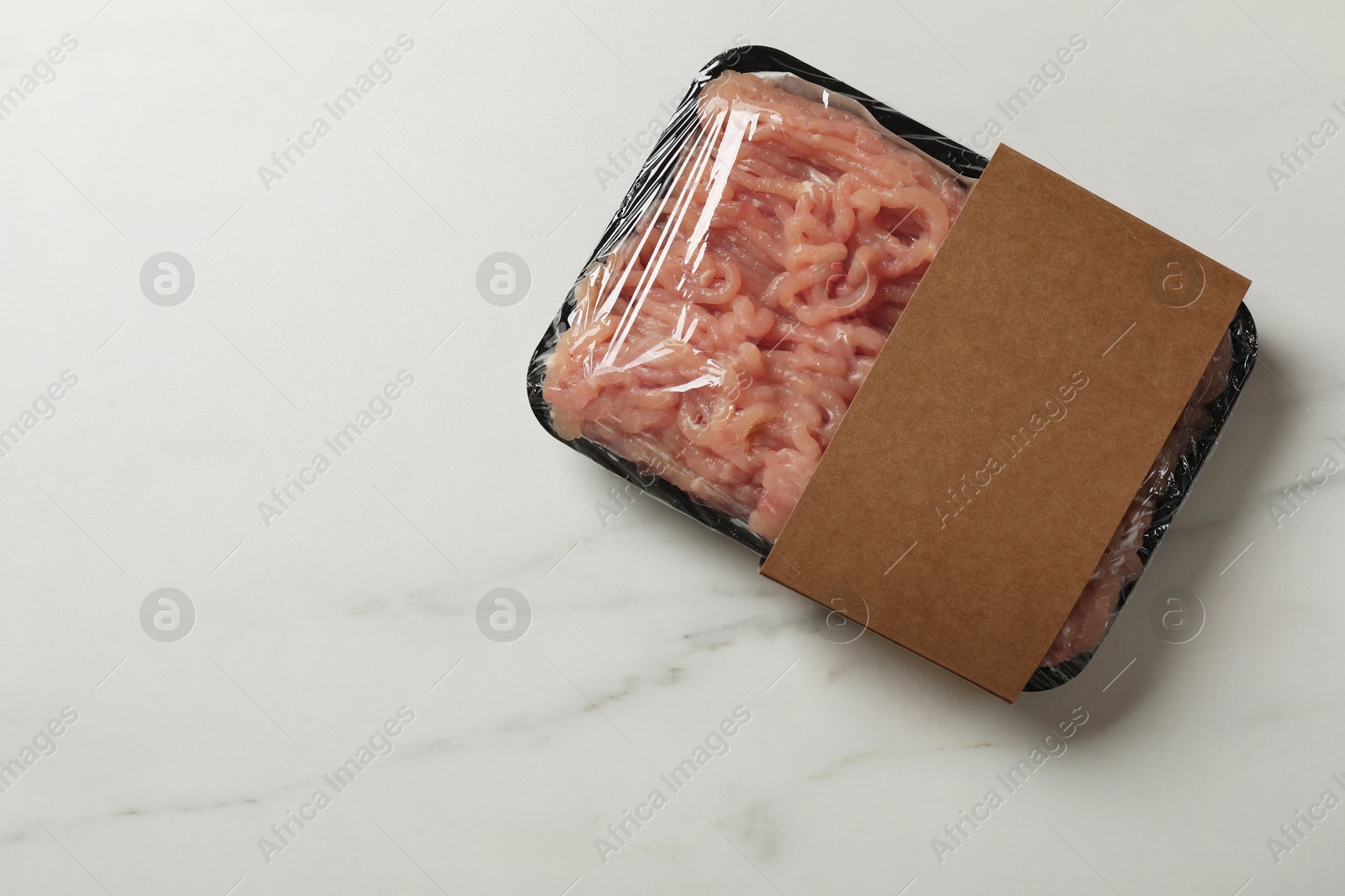 Photo of Plastic pack with fresh minced meat on white marble table, top view