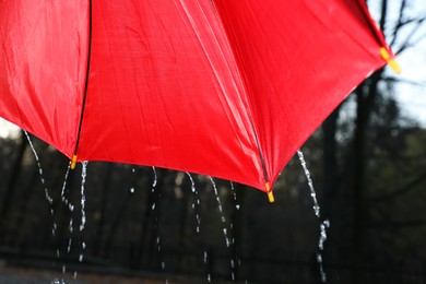 Photo of Open red umbrella under pouring rain outdoors, closeup