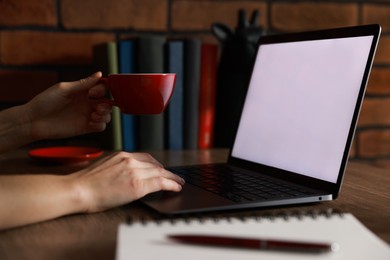 Photo of Woman working with laptop at table in office, closeup