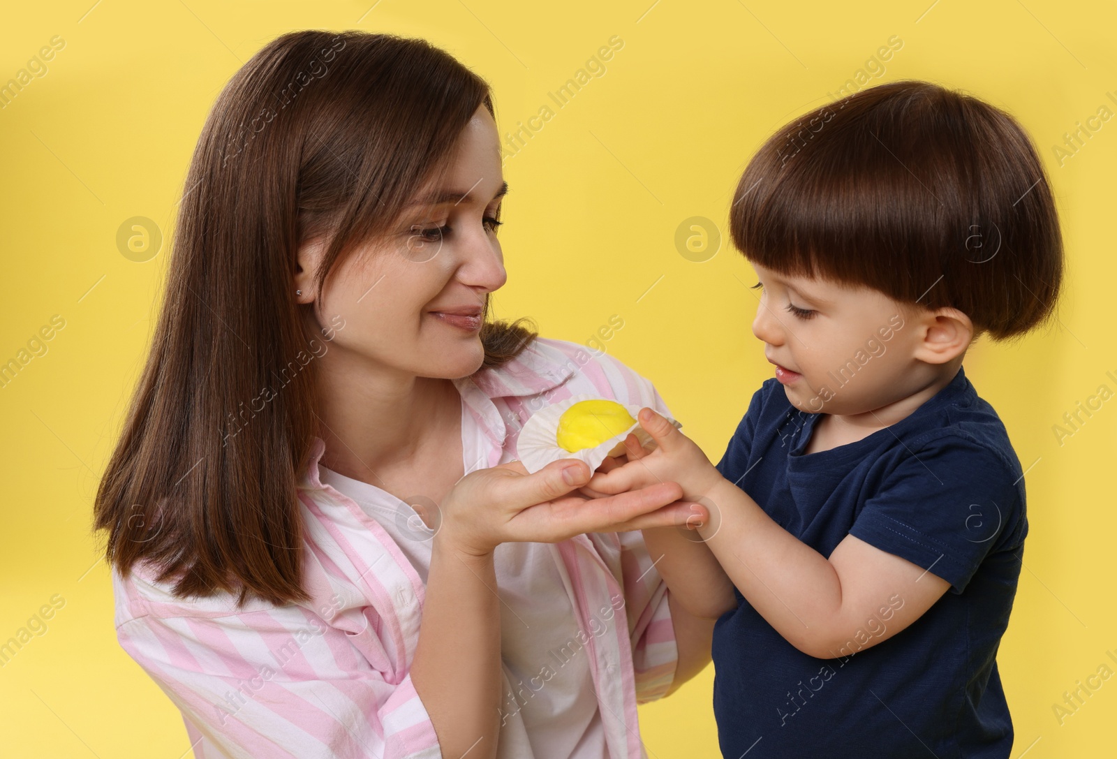 Photo of Mother and baby eating tasty mochi on yellow background