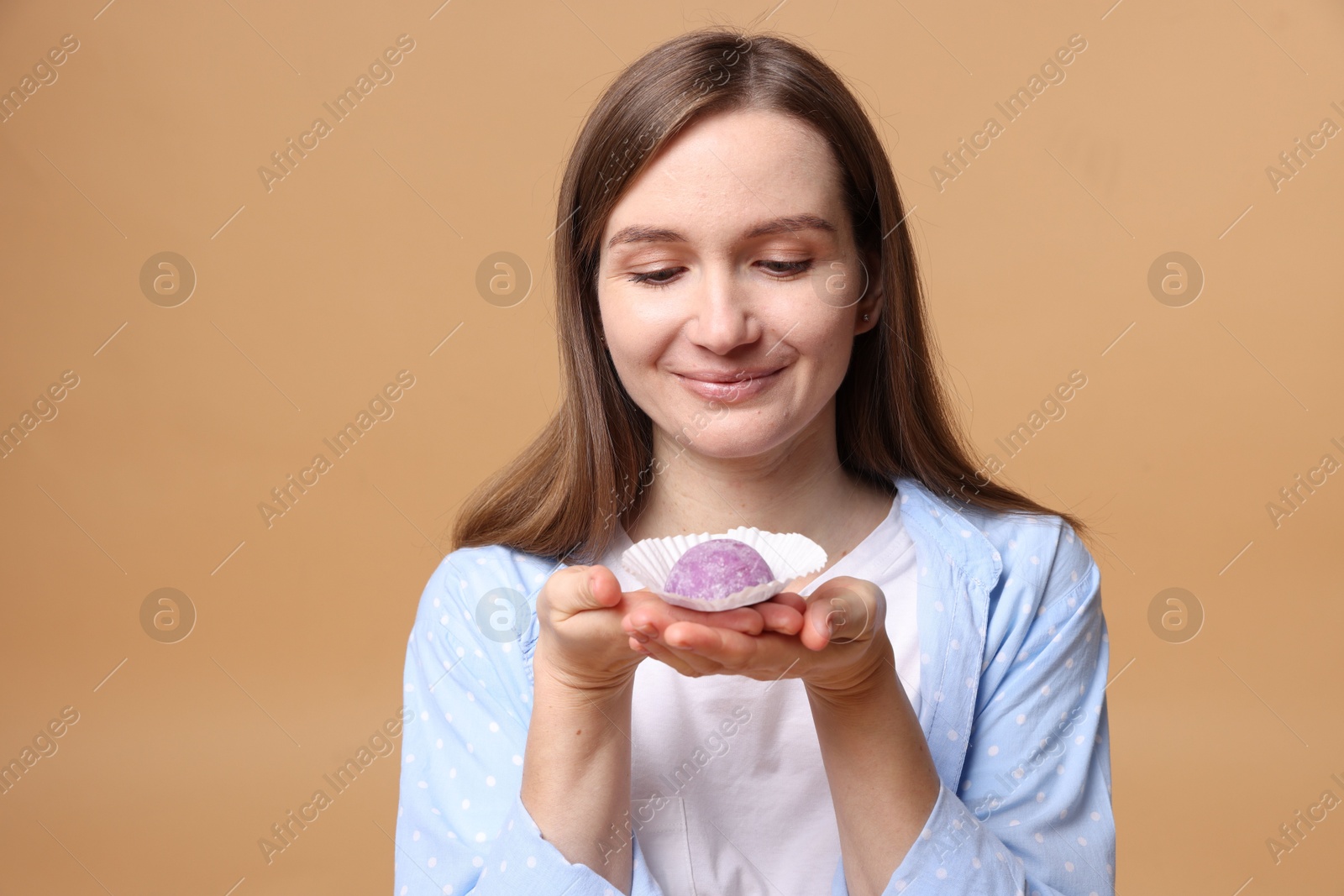 Photo of Woman with tasty mochi on light brown background