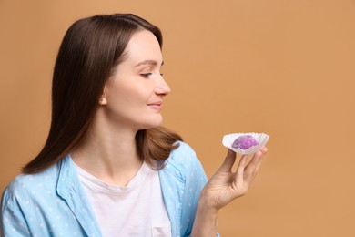 Photo of Woman with tasty mochi on light brown background. Space for text