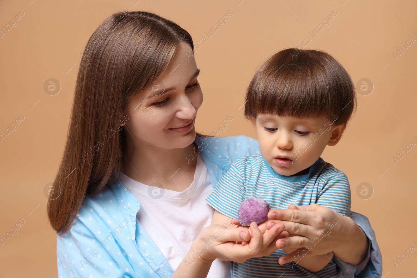 Photo of Mother and baby eating tasty mochi on brown background