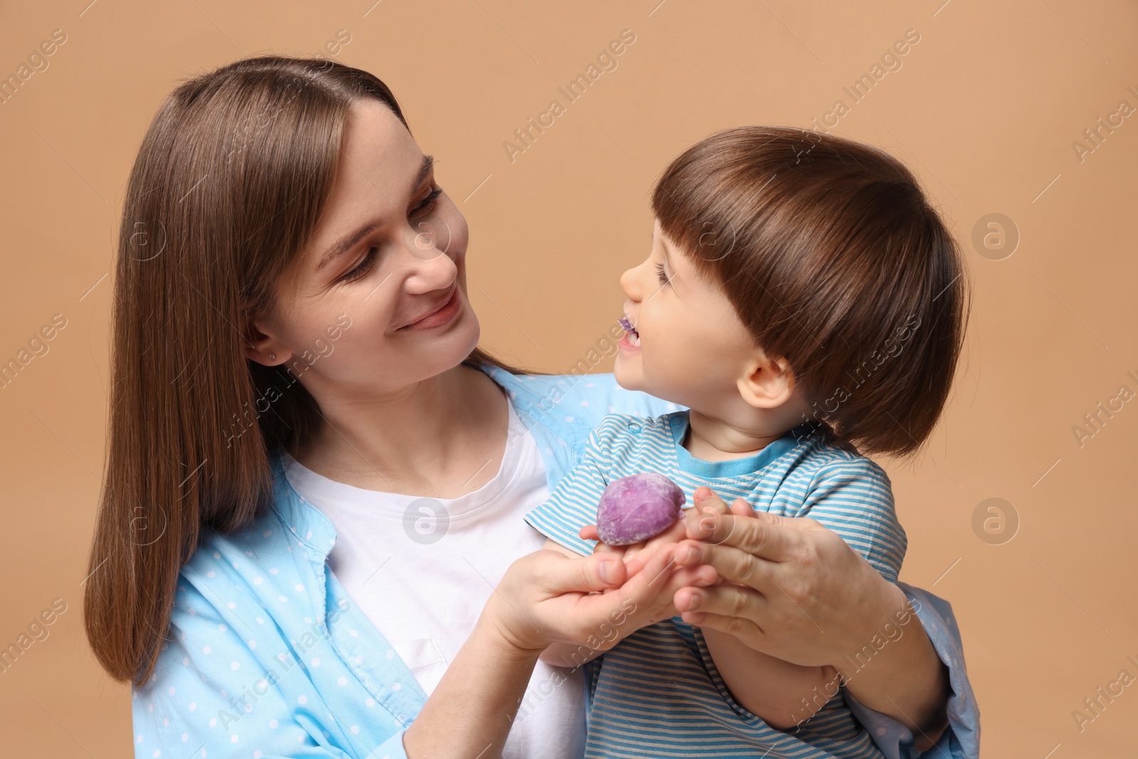 Photo of Mother and baby eating tasty mochi on brown background