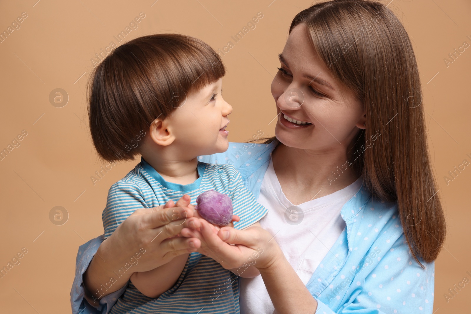 Photo of Mother and baby eating tasty mochi on brown background