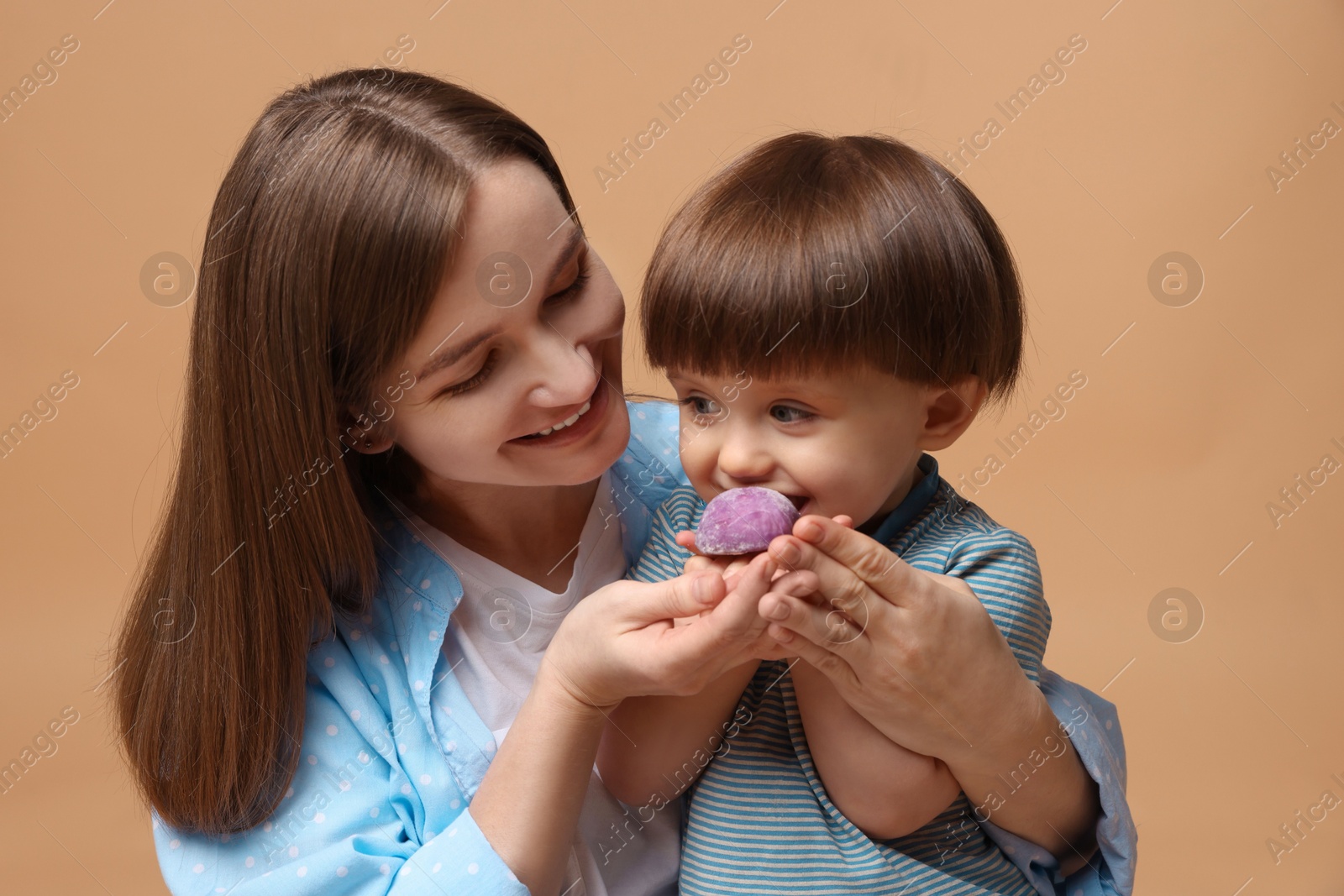 Photo of Mother and baby eating tasty mochi on brown background