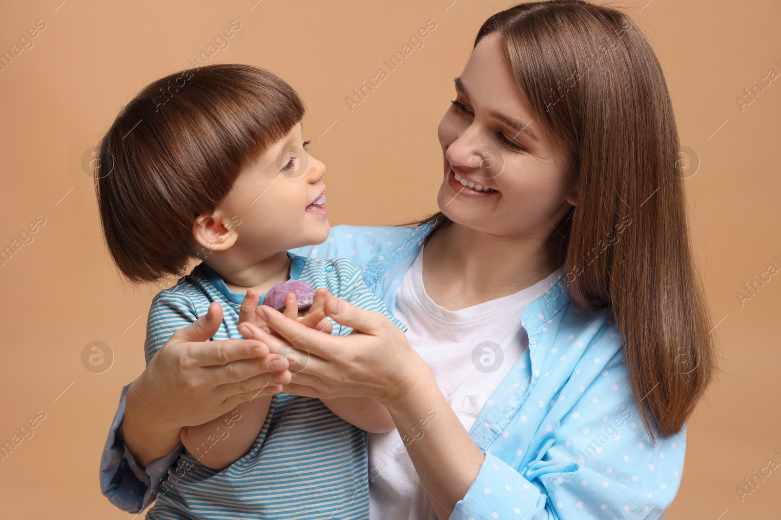 Photo of Mother and baby eating tasty mochi on brown background