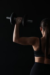 Photo of Woman training with barbells on black background, back view