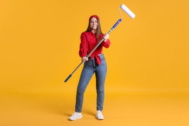 Photo of Woman with paint roller on orange background