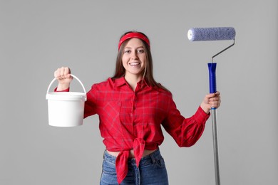 Photo of Woman with roller and bucket of paint on light grey background