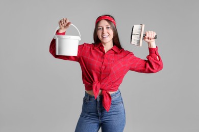 Photo of Woman with brush and bucket of paint on light grey background