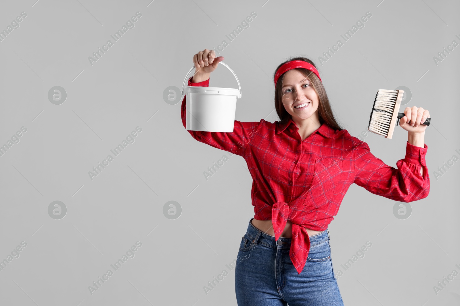 Photo of Woman with brush and bucket of paint on light grey background. Space for text