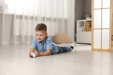 Photo of Little boy playing with toy car at home