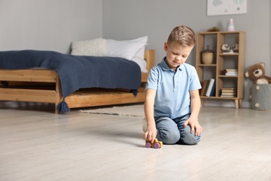 Photo of Little boy playing with toy car at home. Space for text