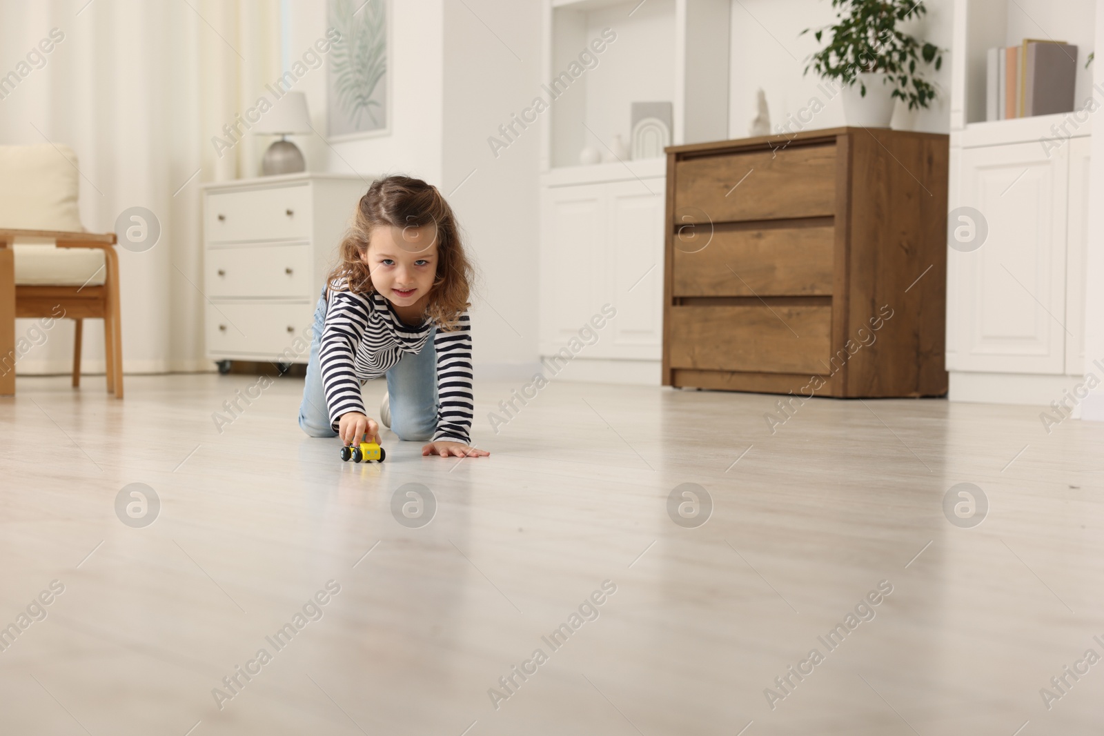 Photo of Little girl playing with toy car on floor at home, space for text