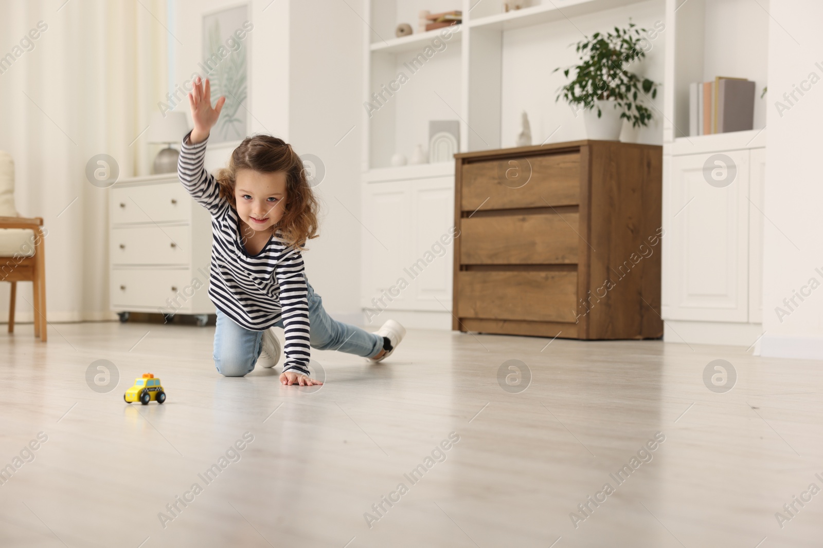 Photo of Little girl playing with toy car on floor at home, space for text