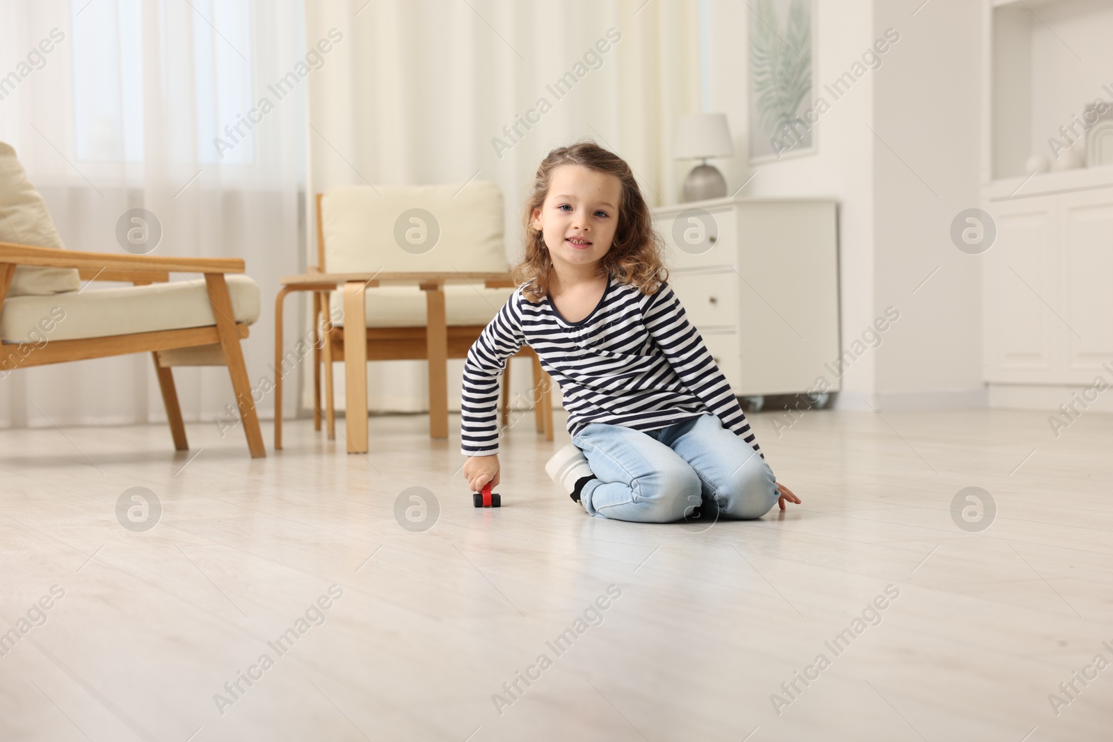 Photo of Little girl playing with toy car on floor at home, space for text