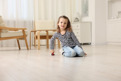 Photo of Little girl playing with toy car on floor at home, space for text