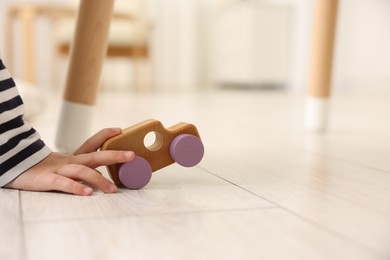 Photo of Little girl playing with toy car on floor at home, closeup. Space for text