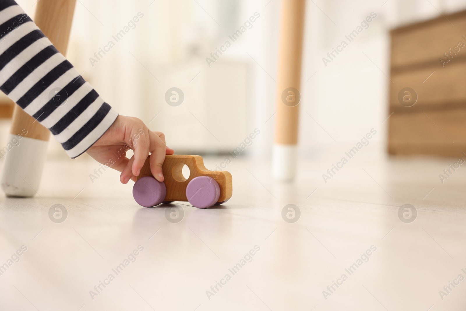 Photo of Little girl playing with toy car on floor at home, closeup. Space for text