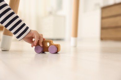 Photo of Little girl playing with toy car on floor at home, closeup. Space for text