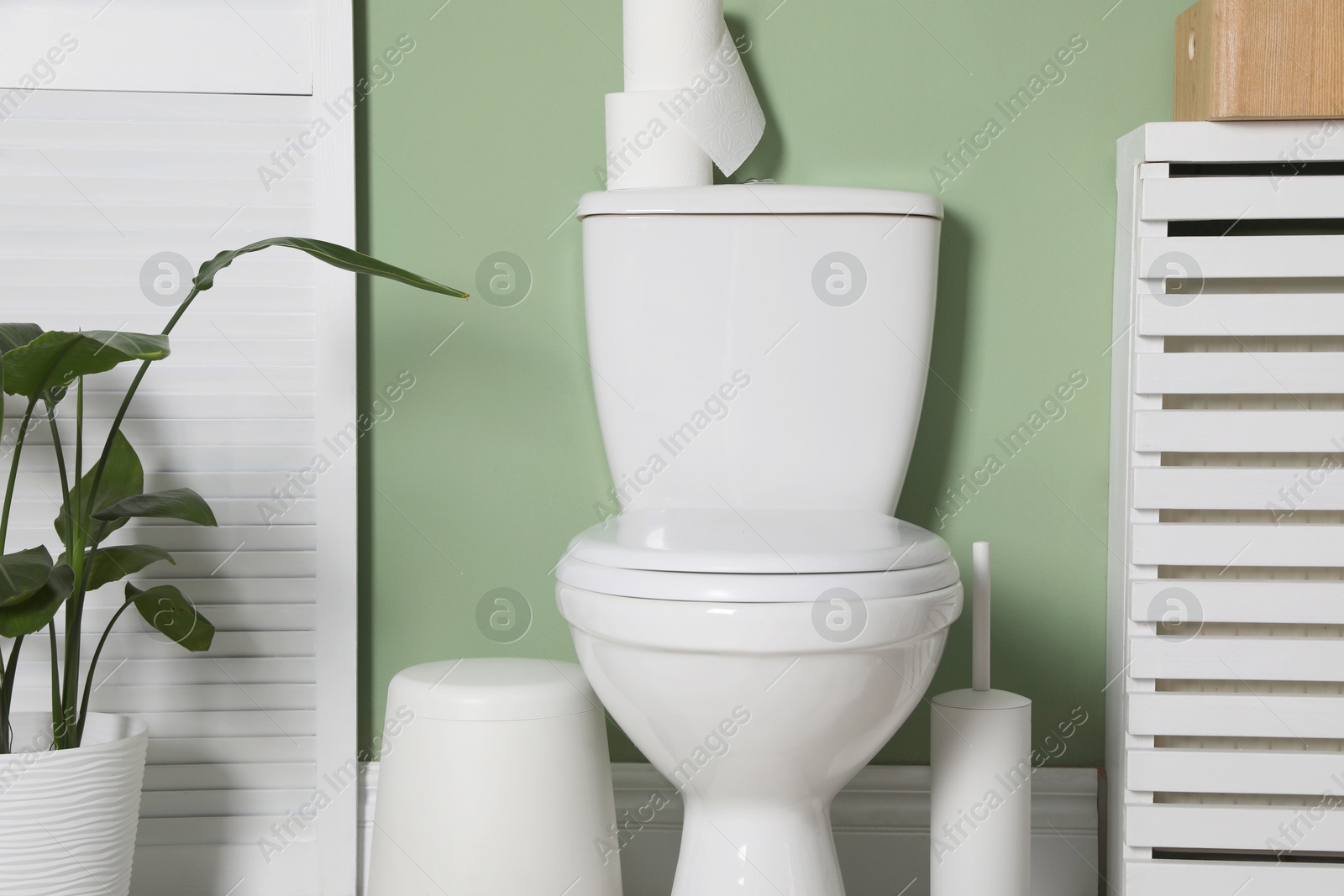 Photo of Ceramic toilet bowl, necessities and folding screen in restroom