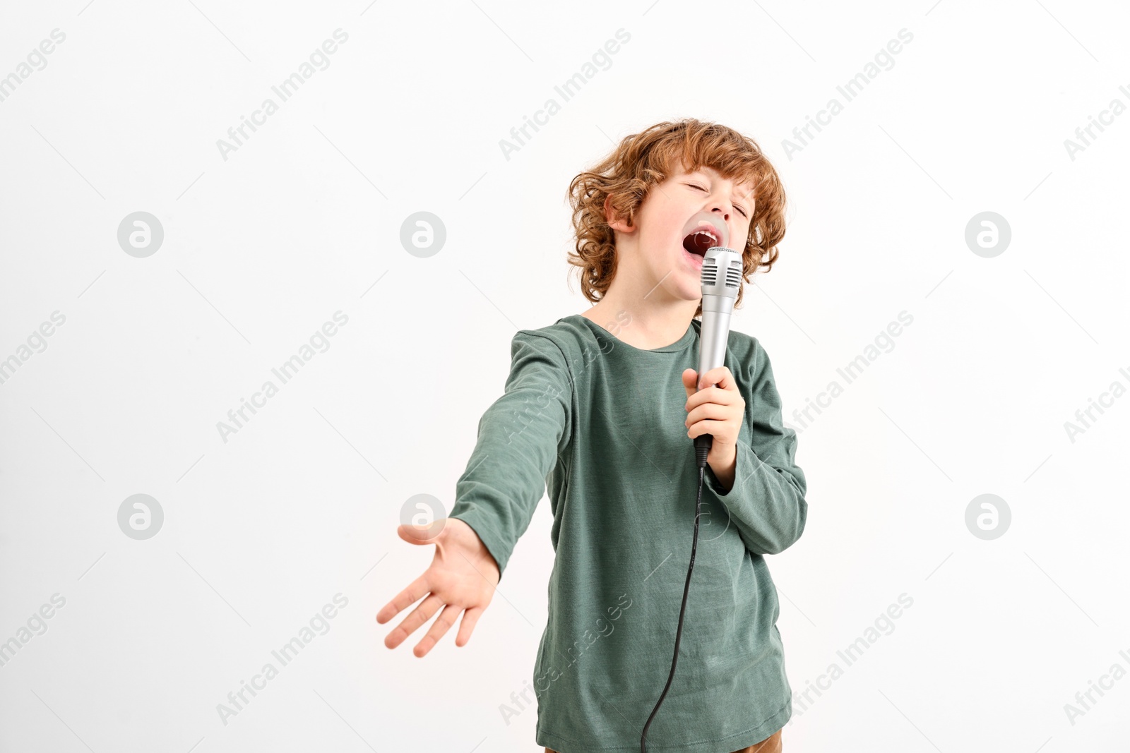 Photo of Little boy with microphone singing on white background