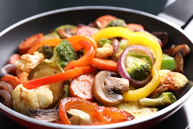 Photo of Frying pan with mix of vegetables and mushrooms on cooktop, closeup