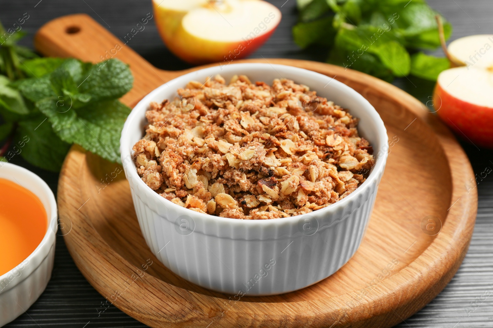 Photo of Delicious apple crisp in bowl and ingredients on black table, closeup