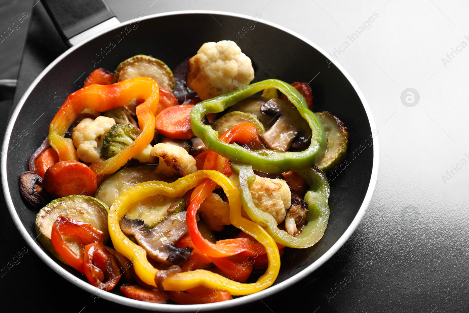 Photo of Frying pan with vegetables and mushrooms on stove, closeup